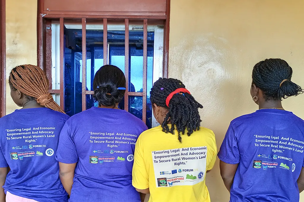 4 women have their back against the camera to show the text Empowering Rural Women through Legal and Economic Advocacy for Land Rights written on their purple t-shirts.