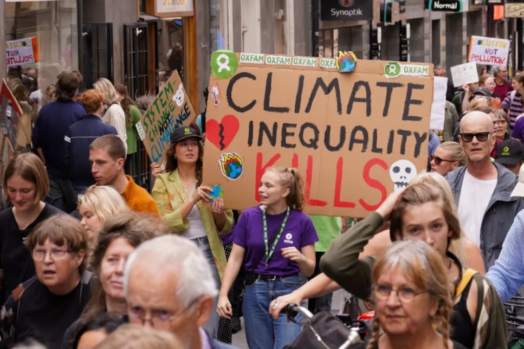 Demonstration på Götgatan i Stockholm. Människor med skyltar. En har texten climate inequality kills.. Text
