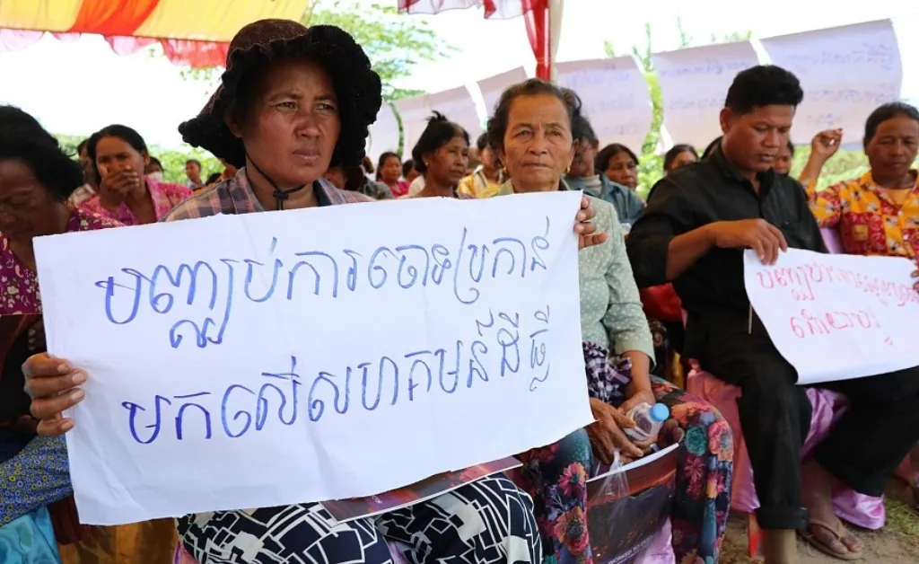 En medlem av Trapeang Chour-kommunen i Kampong Speu-provinsen vid ett IHRD-evenemang den 8 december 2023 håller en skylt som lyder: "Stoppa juridiska anklagelser mot landsamhällen"