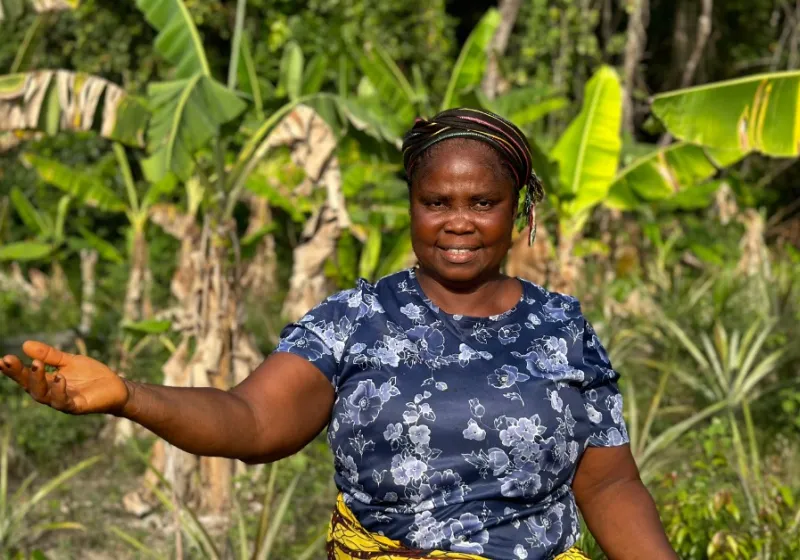 Kermah G. Tokpah stands on her piece of land and smiles into the camera.