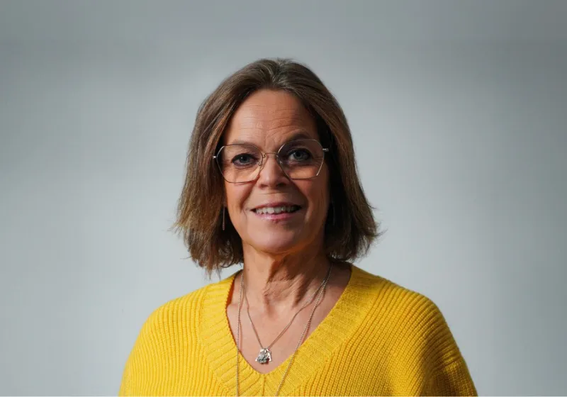 Anna ler mot kameran iklädd en gul tröja.