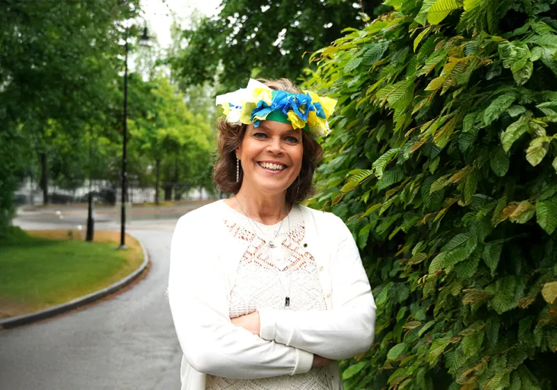 Anna stenvinkel ler mot kameran med en midsommarkrans i papper på huvudet.