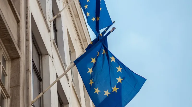 EU flaggor hänger på flaggstänger ut från en byggnad.