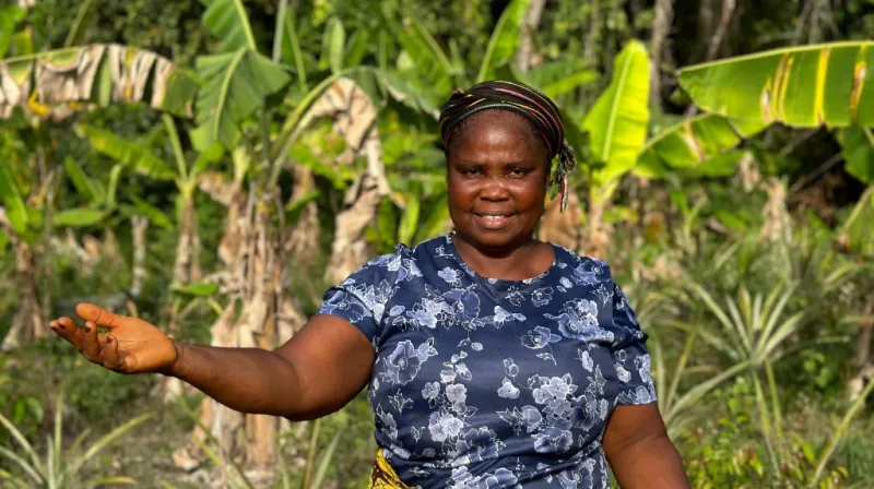 Kermah G. Tokpah stands on her piece of land and smiles into the camera.