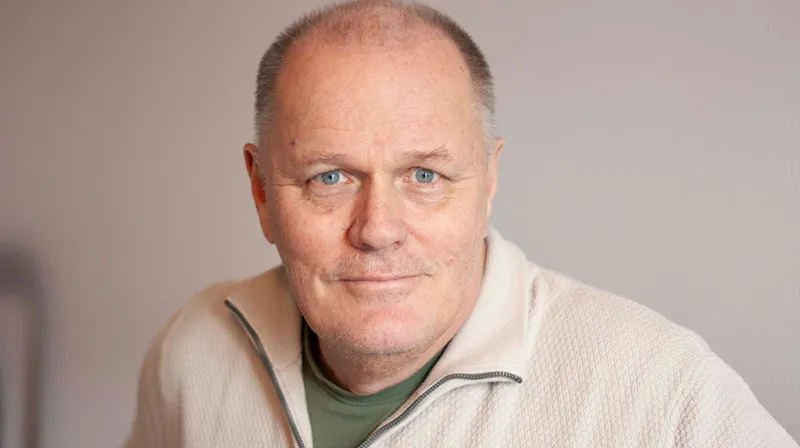 Göran ler in i kameran iklädd en vit tröja.